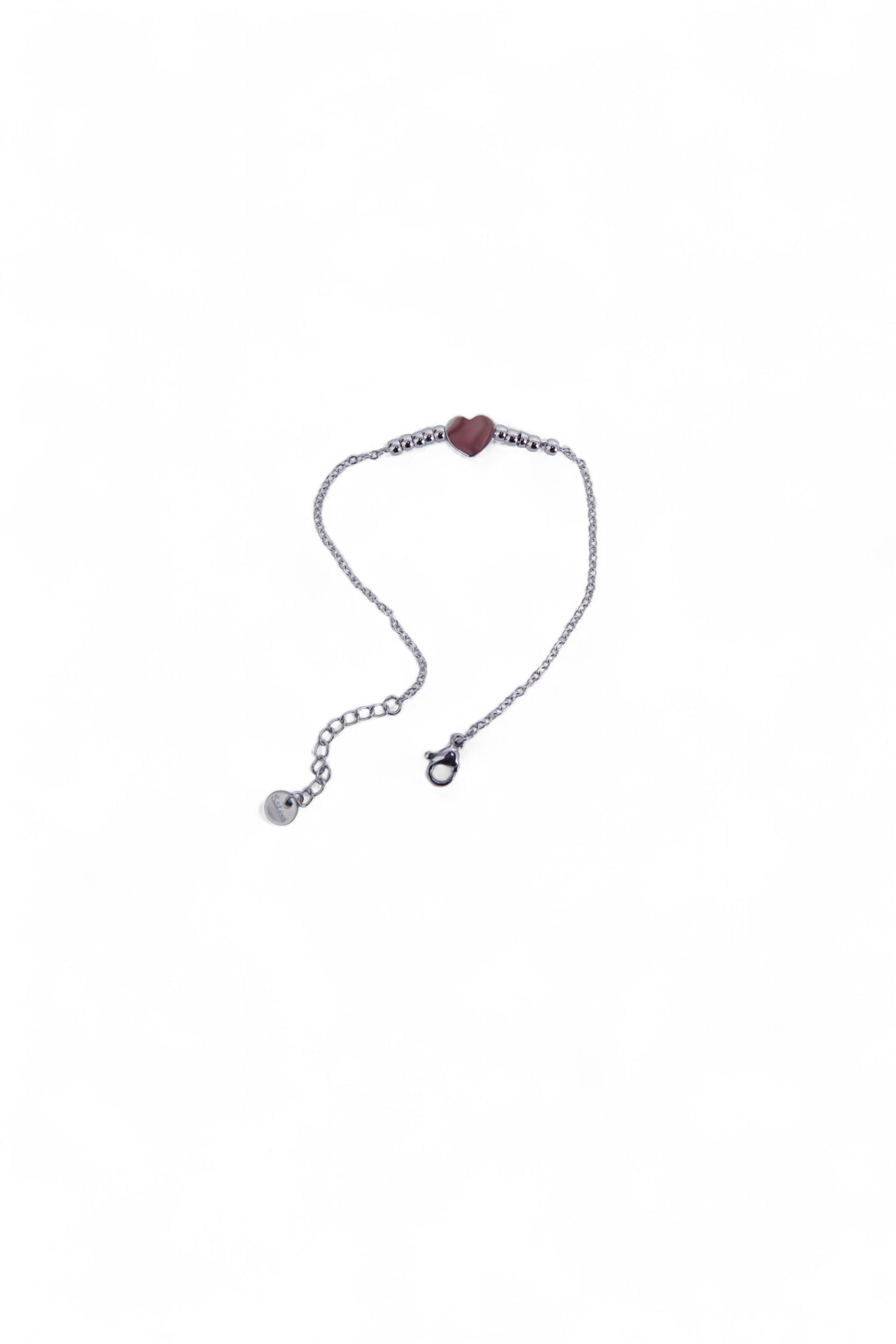 Brățară argintie din oțel inoxidabil, cu pandantiv inimă și biluțe mici, așezată delicat pe fundal alb.