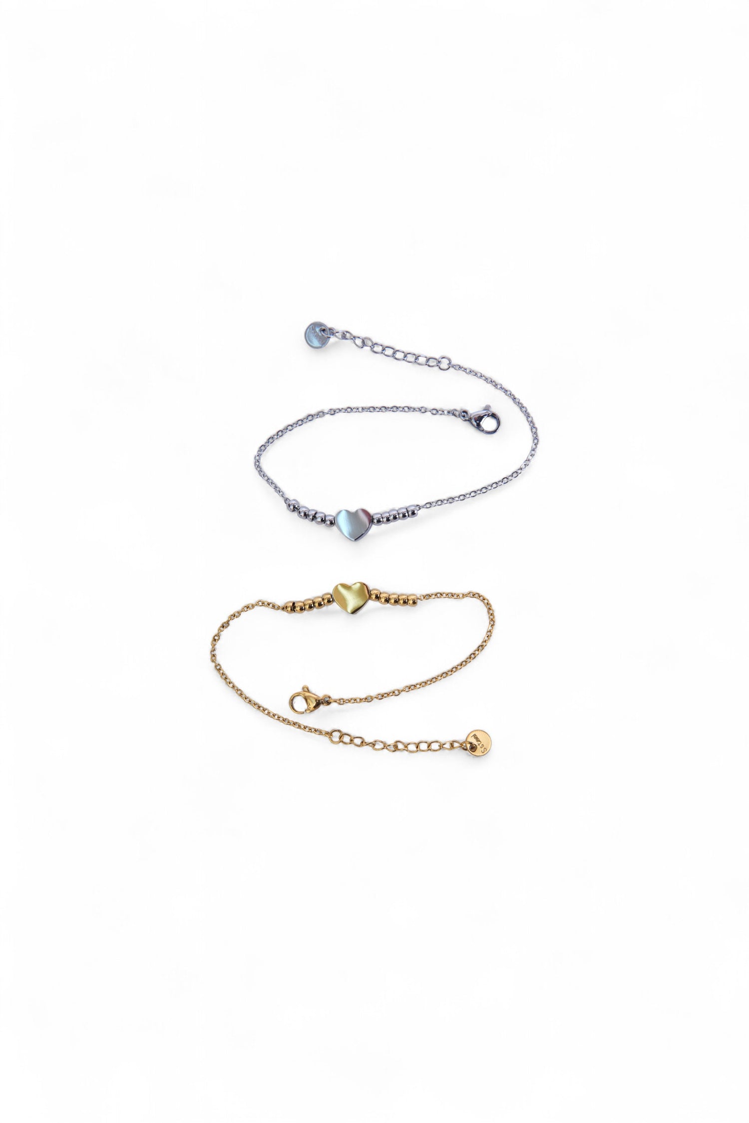 Două brățări din oțel inoxidabil, una argintie și una aurie, cu inimă centrală și lanț fin, așezate pe fundal alb, vedere de ansamblu.