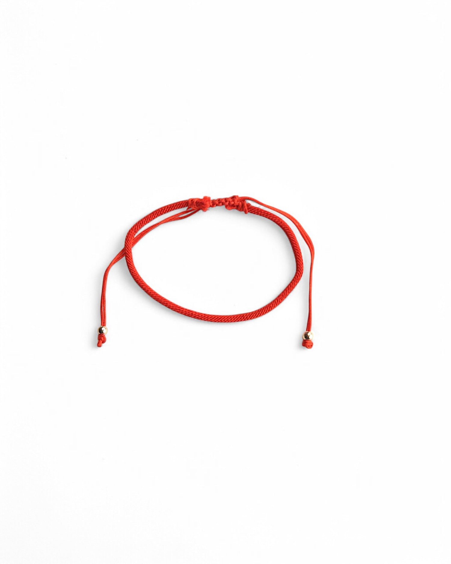  Brățară minimalistă din șnur roșu reglabil, accesorizată cu biluțe aurii.
