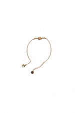 Brățară auriu subțire din oțel inoxidabil, cu medalion trifoi, fotografiată în formă circulară.