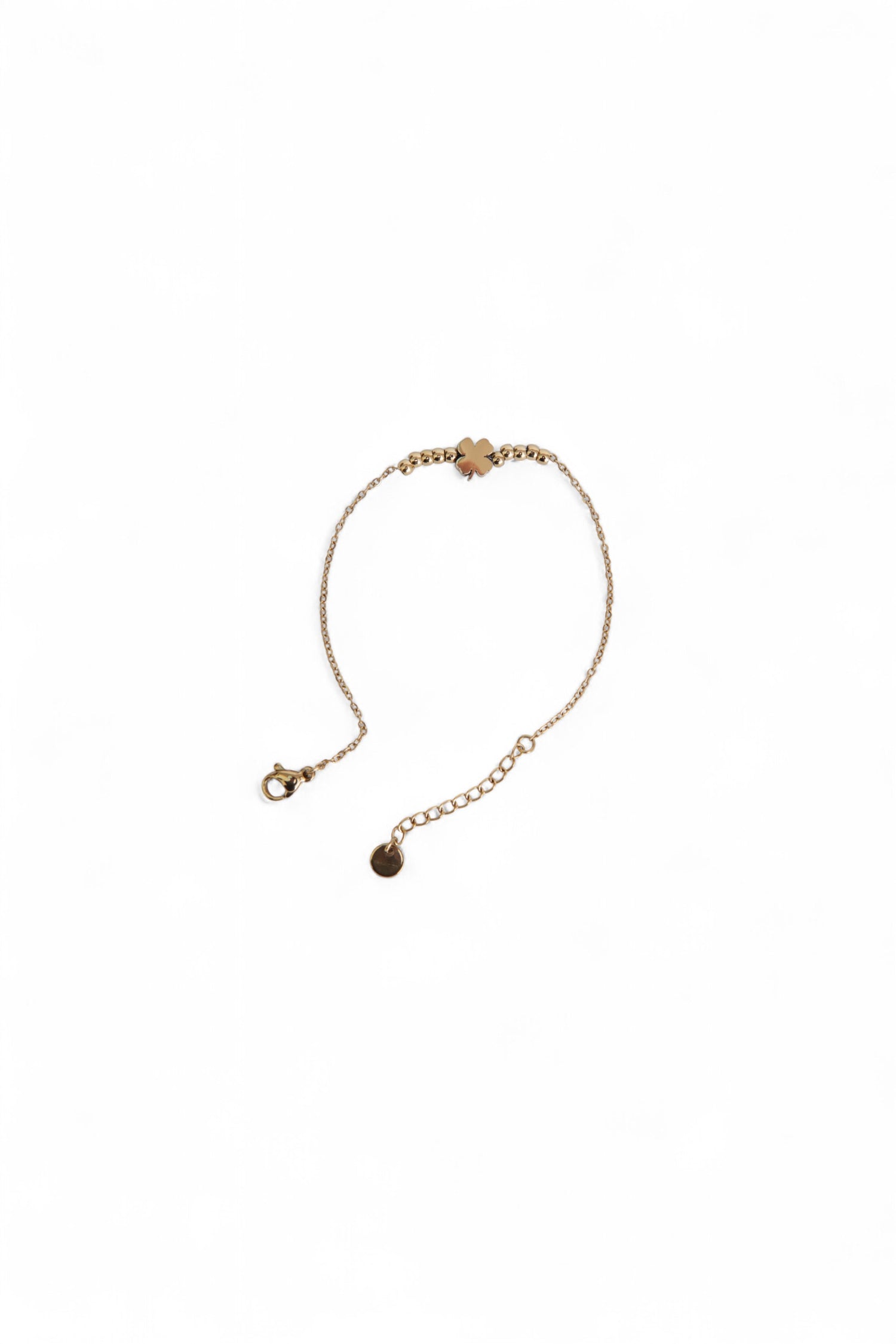 Brățară auriu subțire din oțel inoxidabil, cu medalion trifoi, fotografiată în formă circulară.