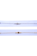 Prim-plan cu brățara din oțel inoxidabil cu simbol trifoi, întinsă pe fundal albastru deschis.