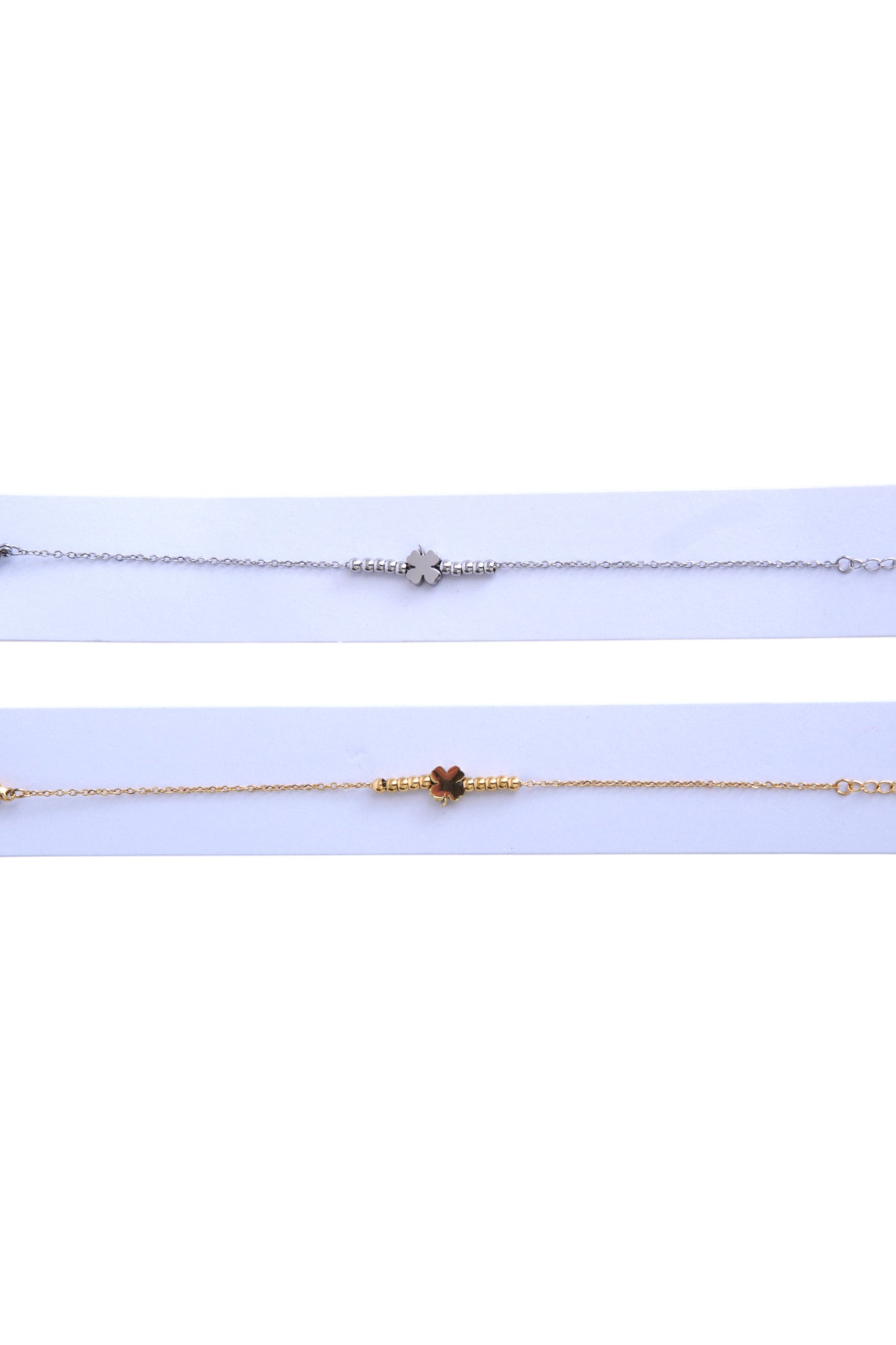 Prim-plan cu brățara din oțel inoxidabil cu simbol trifoi, întinsă pe fundal albastru deschis.