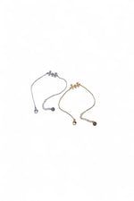 Set de două brățări cu simbol familie, una aurie și una argintie, fotografiate împreună.