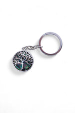 Breloc rotund din metal, cu simbolul Arborele Vieții și inserții sidefate irizate, pe fundal alb.