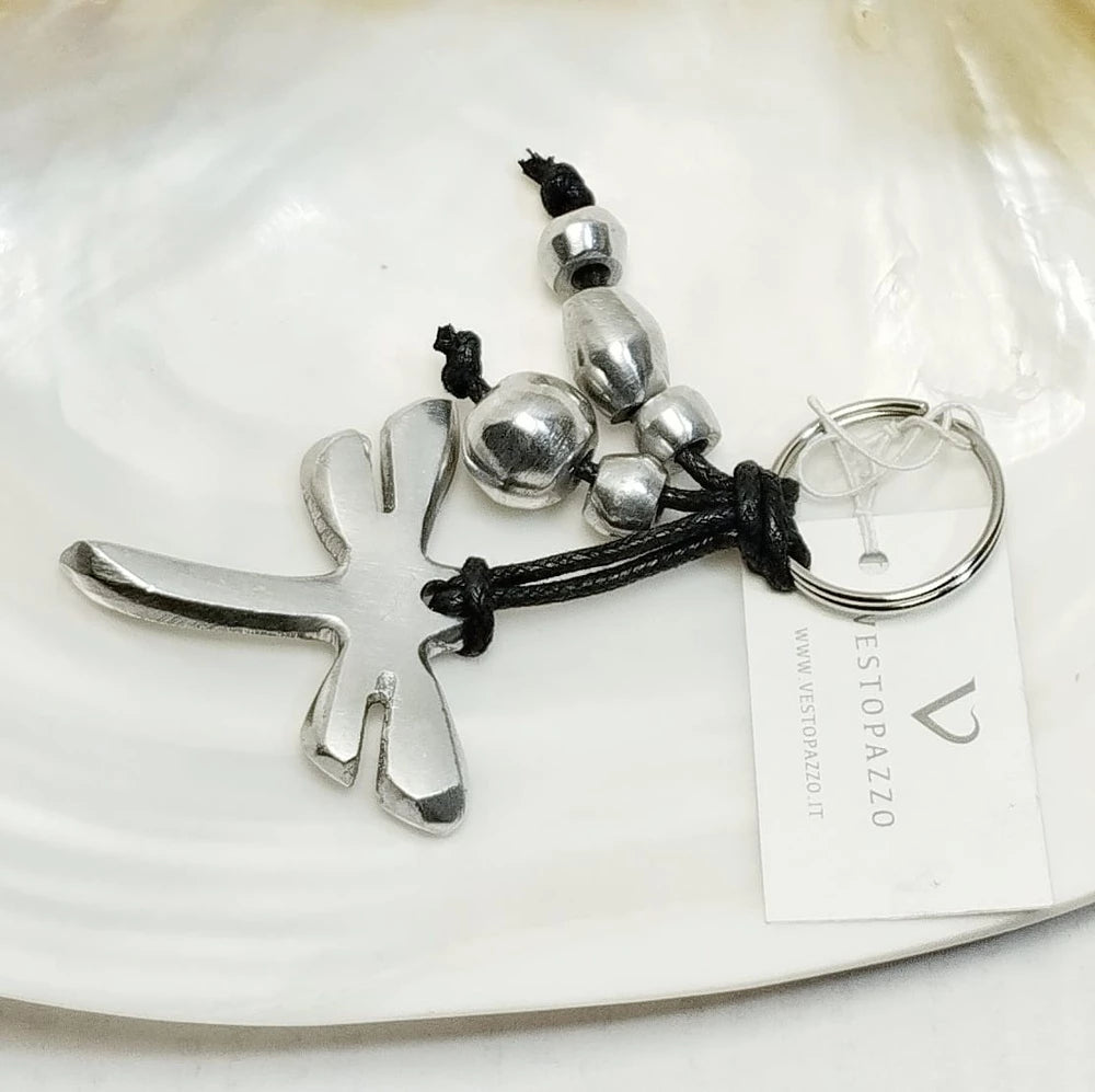 Breloc cu pandantiv în formă de libelulă din aluminiu reciclat, decorat cu mărgele metalice pe șnur negru, prezentat pe fundal alb.