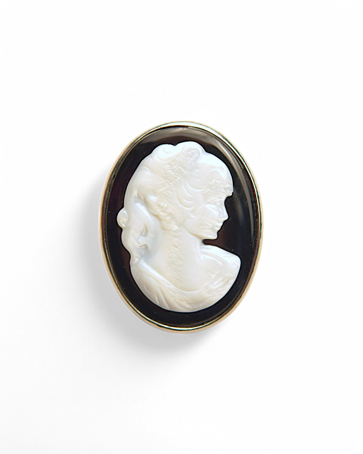 Broșă camee mare, ovală, cu un profil sculptat în alb pe un fundal negru, încadrată într-o ramă aurie elegantă.
