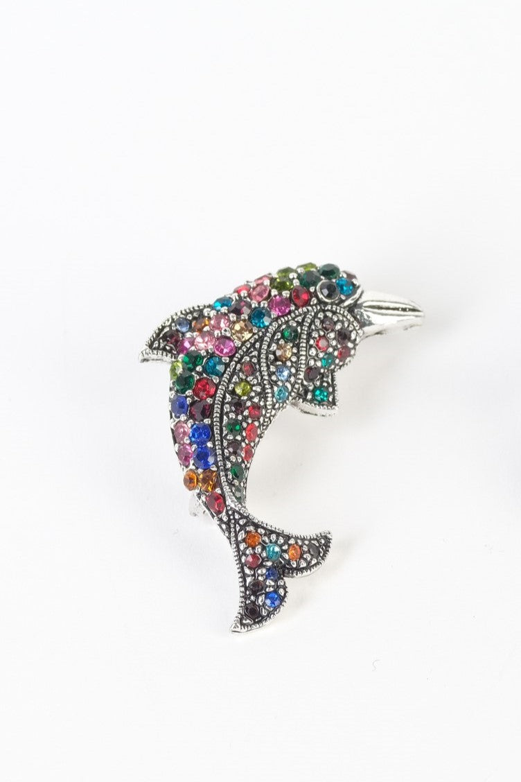 Broșă elegantă în formă de delfin, decorată cu strasuri multicolore, pe fundal alb.