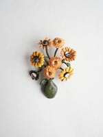 Brosă decorativă în formă de vază cu flori galbene, design artistic cu detalii florale și finisaj delicat.
