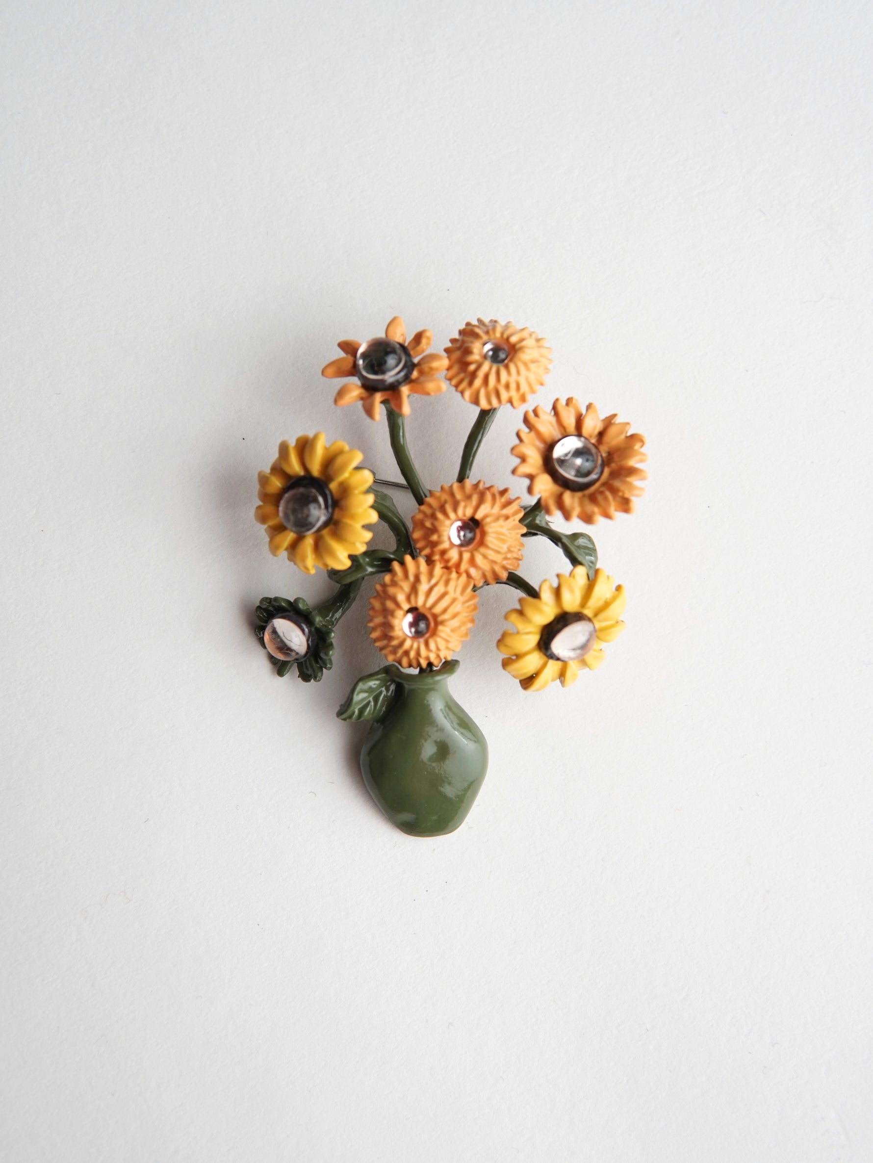 Brosă decorativă în formă de vază cu flori galbene, design artistic cu detalii florale și finisaj delicat.