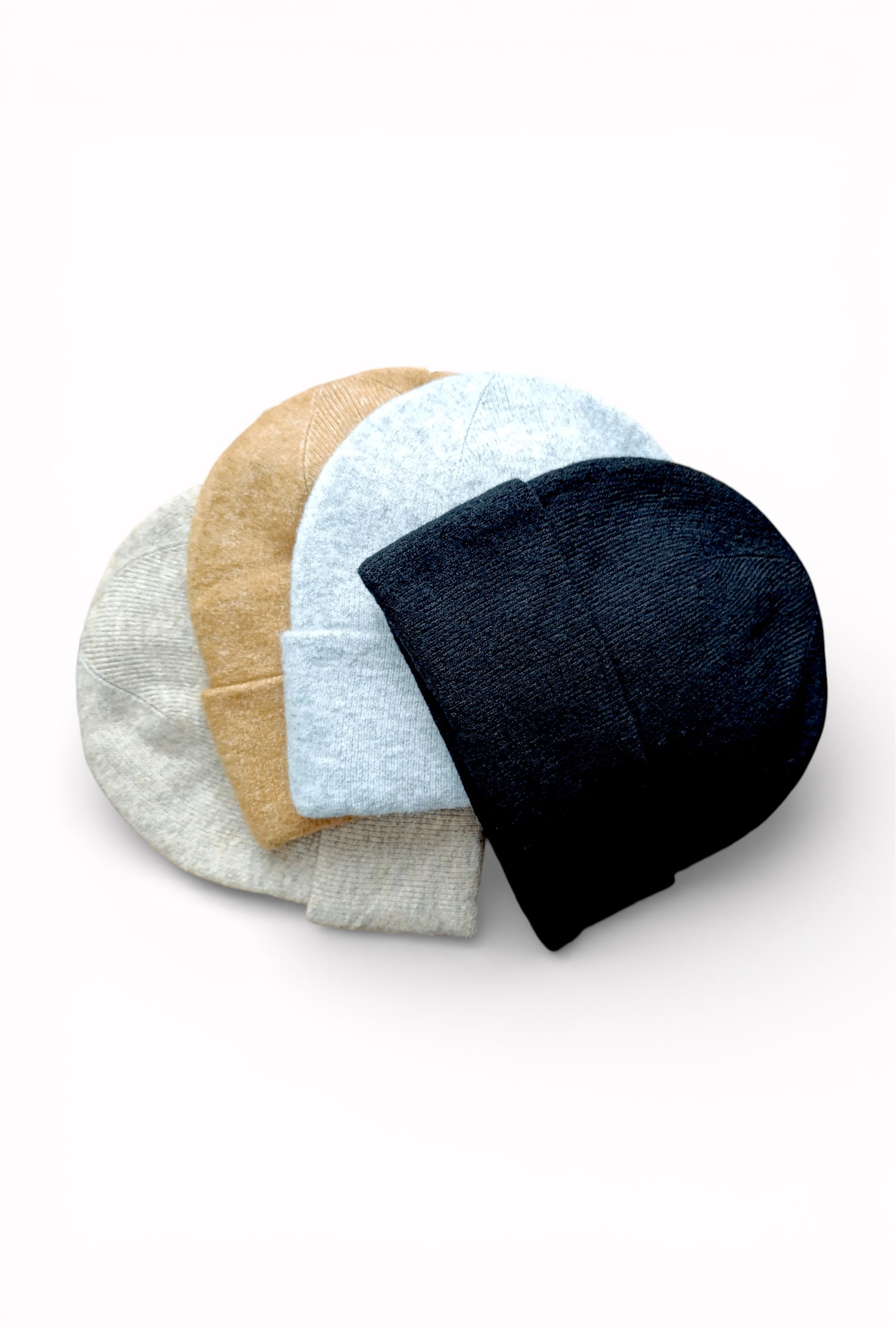 Set de căciuli tricotate în nuanțe neutre și naturale, așezate suprapus, cu design minimalist.