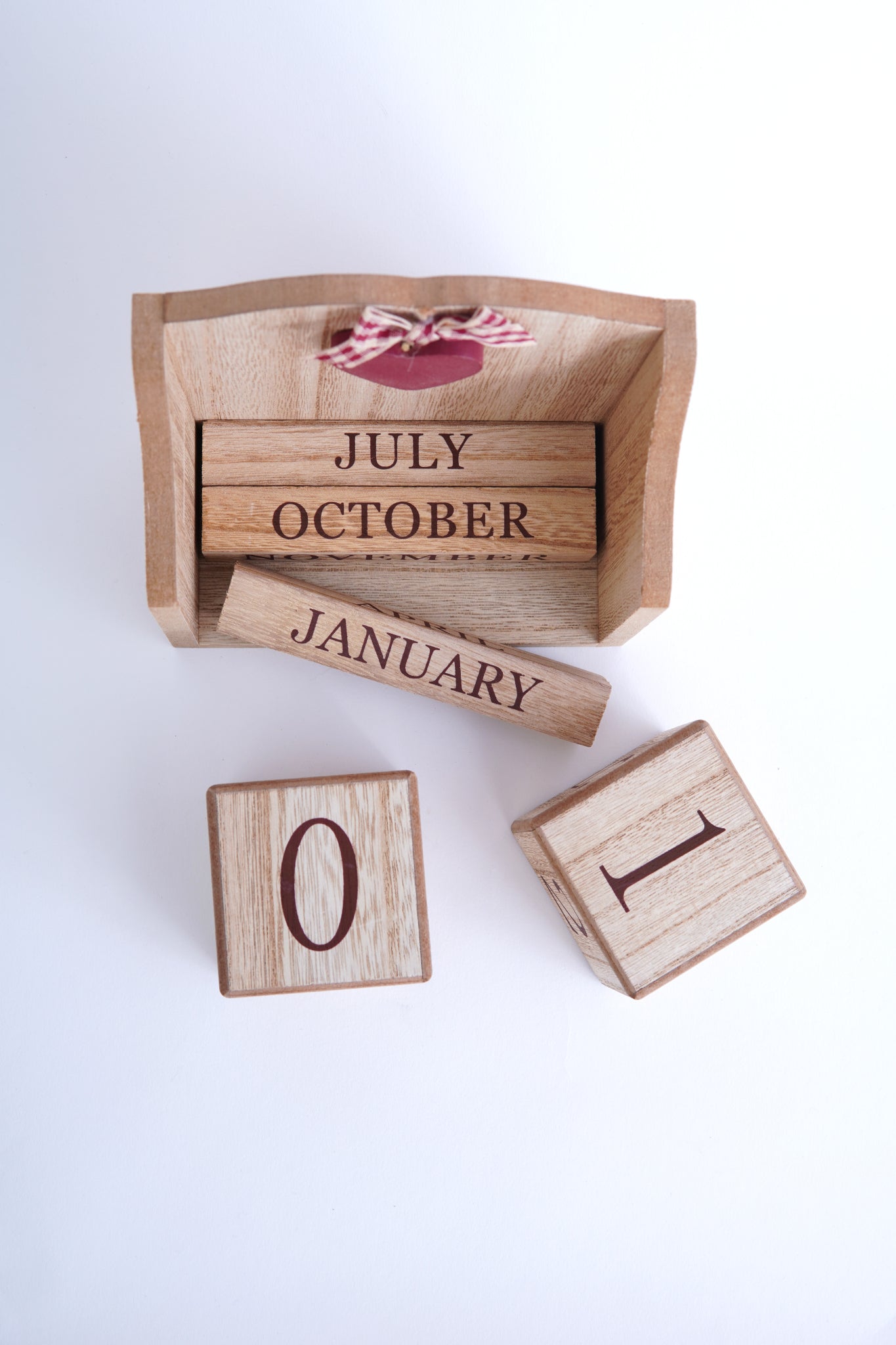 Calendar din lemn cu piesele detașate, cuburi cu numere și bare inscripționate cu luni, aranjate lângă suportul rustic decorat cu inimă roșie.