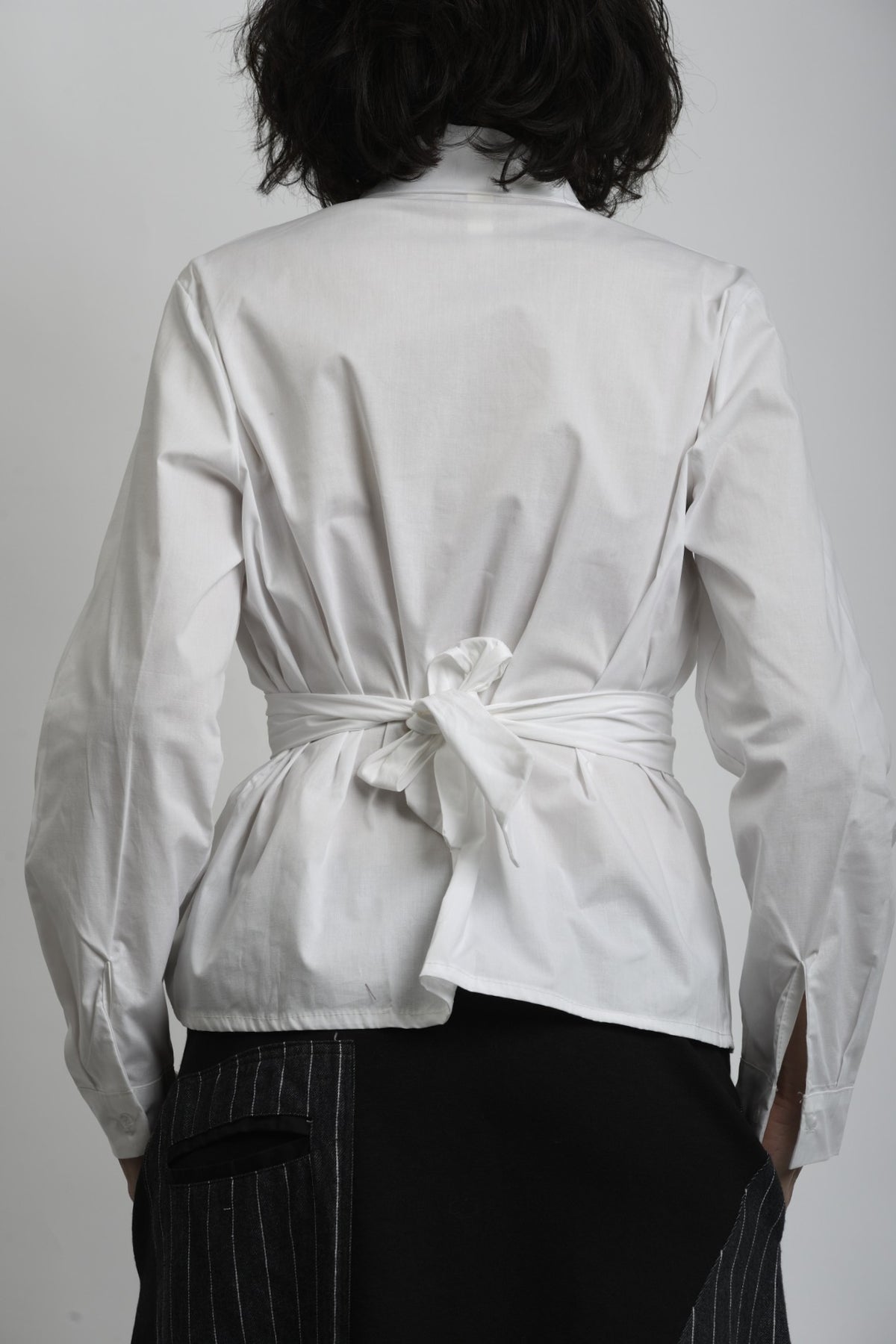 Detaliu cămașă albă cu închidere petrecută și cusături curate, accent pe talie.