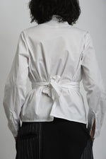 Detaliu cămașă albă cu închidere petrecută și cusături curate, accent pe talie.