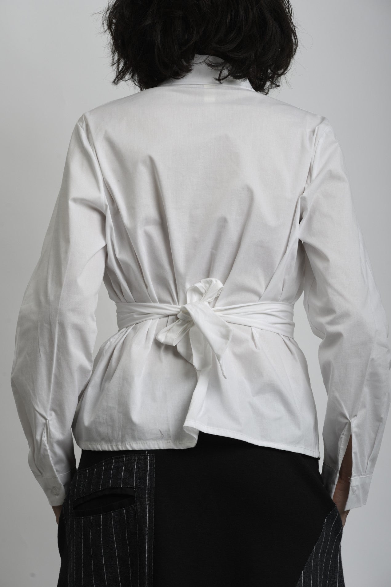 Detaliu cămașă albă cu închidere petrecută și cusături curate, accent pe talie.