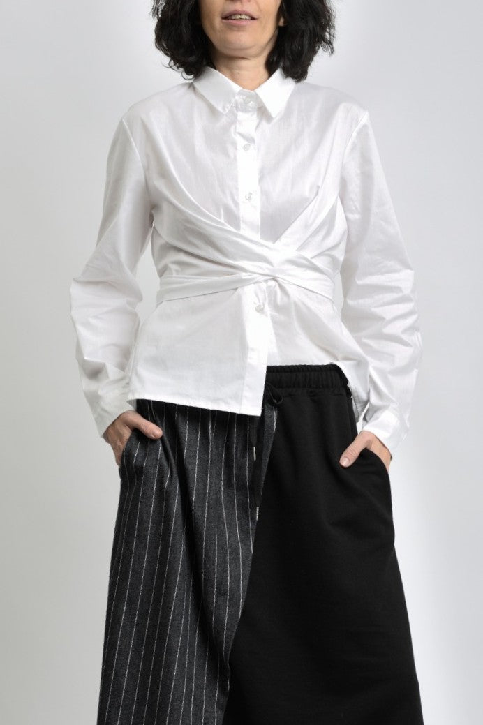 Cămașă albă din bumbac cu detaliu petrecut, purtată într-o ținută casual-elegantă.