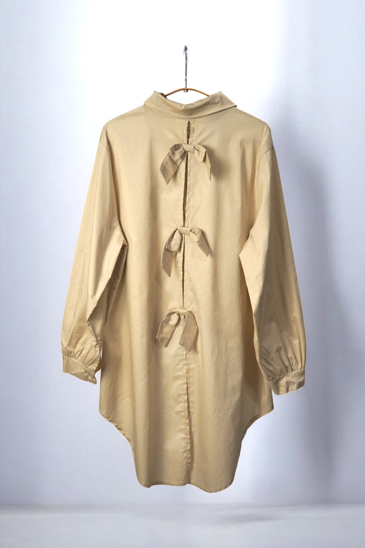 Cămașă asimetrică bej cu detalii elegante la spate, închidere cu fundițe.
