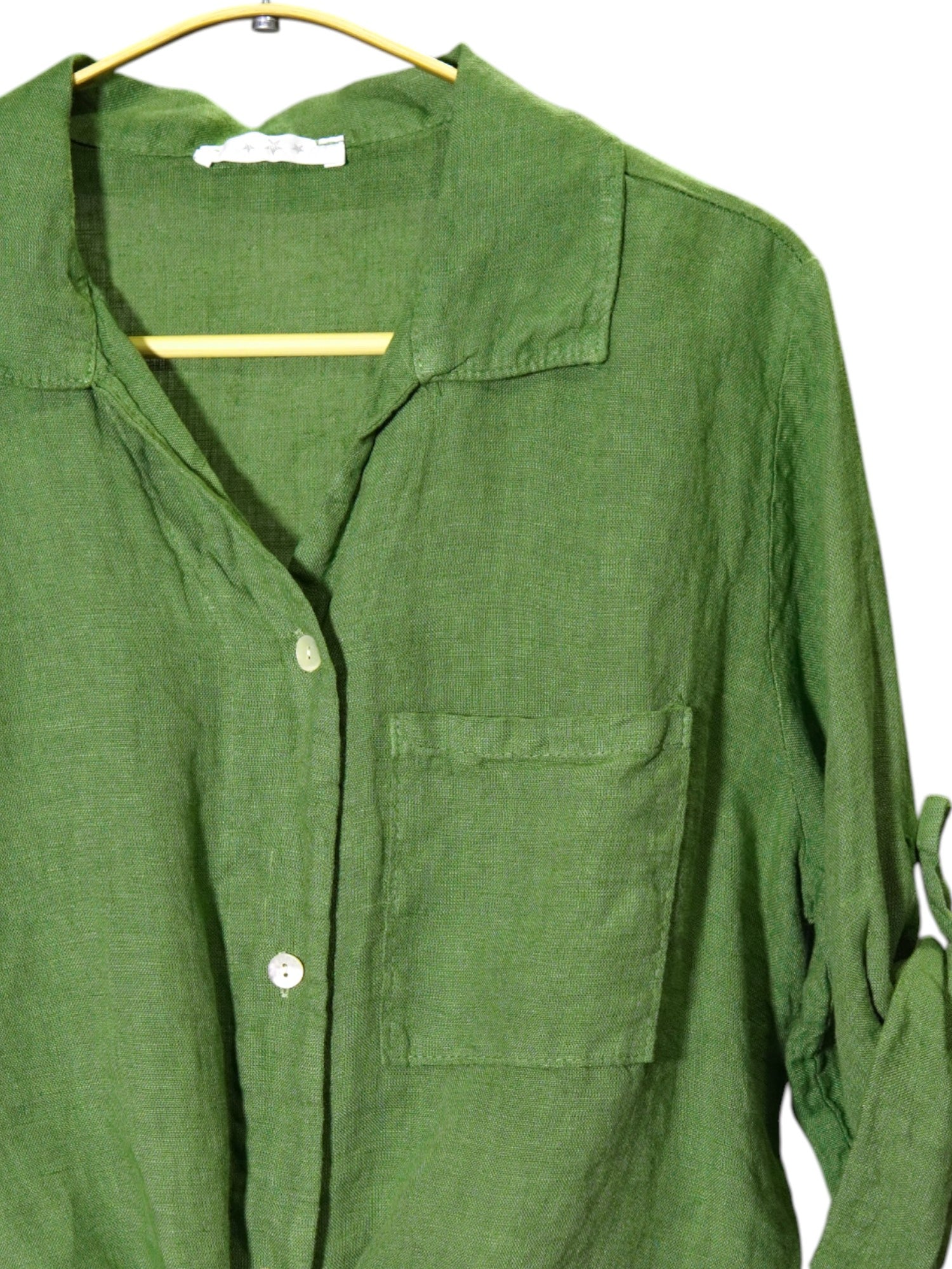 Prim-plan pe materialul și nasturii sidefați ai unei cămăși verzi din in