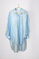 Cămașă oversized bleu pastel, din material ușor și transparent, afișată pe umeraș, fundal alb.