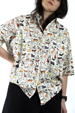 Detaliu de imprimeu cu pisici naive pe cămașă albă, cu textură ușoară și croială lejeră.