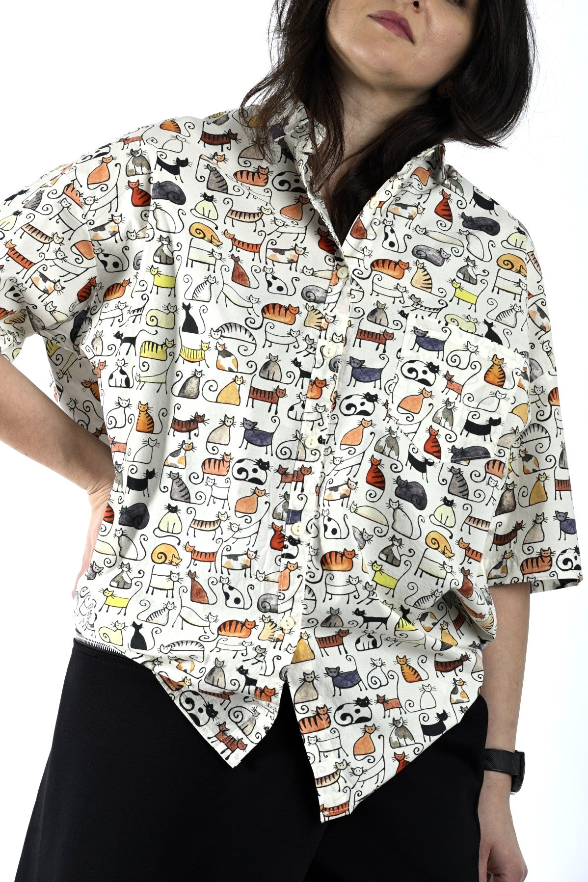Detaliu de imprimeu cu pisici naive pe cămașă albă, cu textură ușoară și croială lejeră.