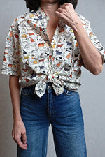 Cămașă cu print artistic purtată casual, legată în față, pentru un look relaxat de vară.