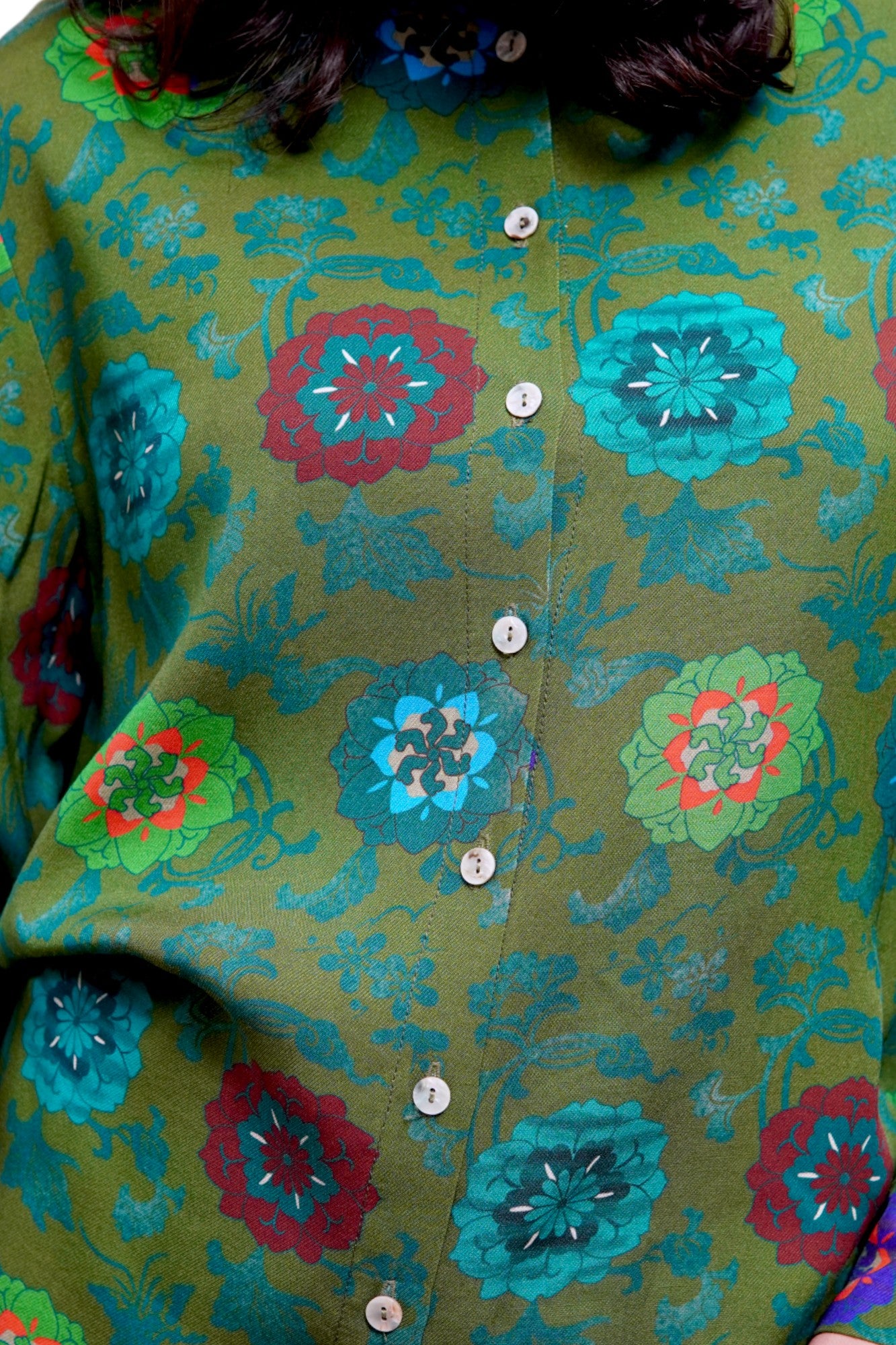 Prim-plan cu imprimeu floral roșu și turcoaz pe material verde din viscoză