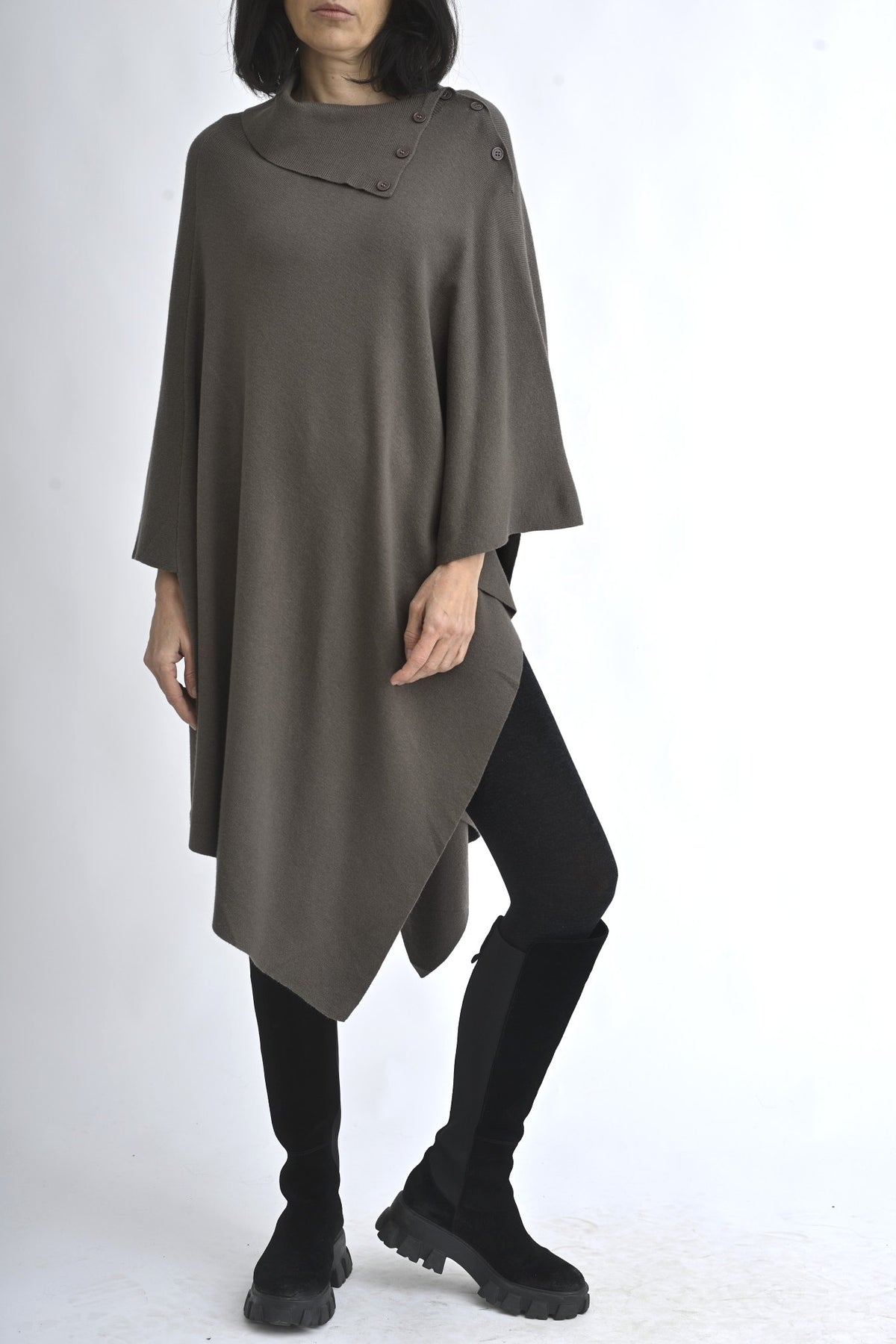 Vedere completă a unei cape tricotate maro, purtată cu colanți și cizme