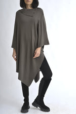 Vedere completă a unei cape tricotate maro, purtată cu colanți și cizme