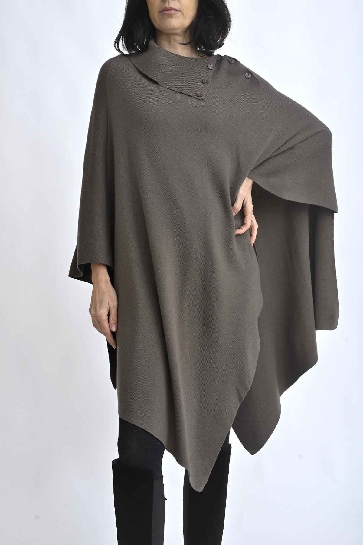 Vedere completă a unei cape tricotate maro, purtată cu colanți și cizme