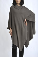 Vedere completă a unei cape tricotate maro, purtată cu colanți și cizme