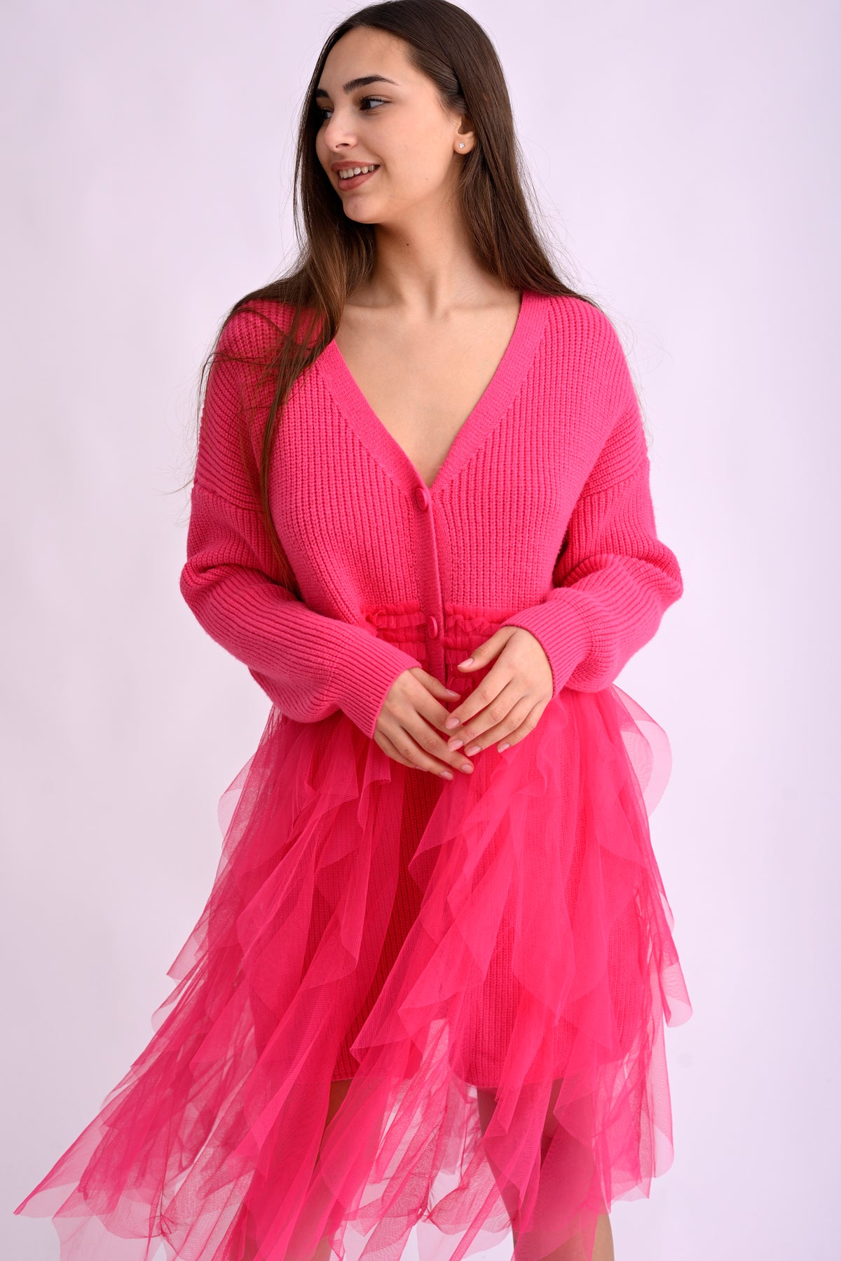 Model poartă un cardigan roz intens cu franjuri lungi, din material moale și texturat, prezentare din față.