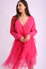 Model poartă un cardigan roz intens cu franjuri lungi, din material moale și texturat, prezentare din față.