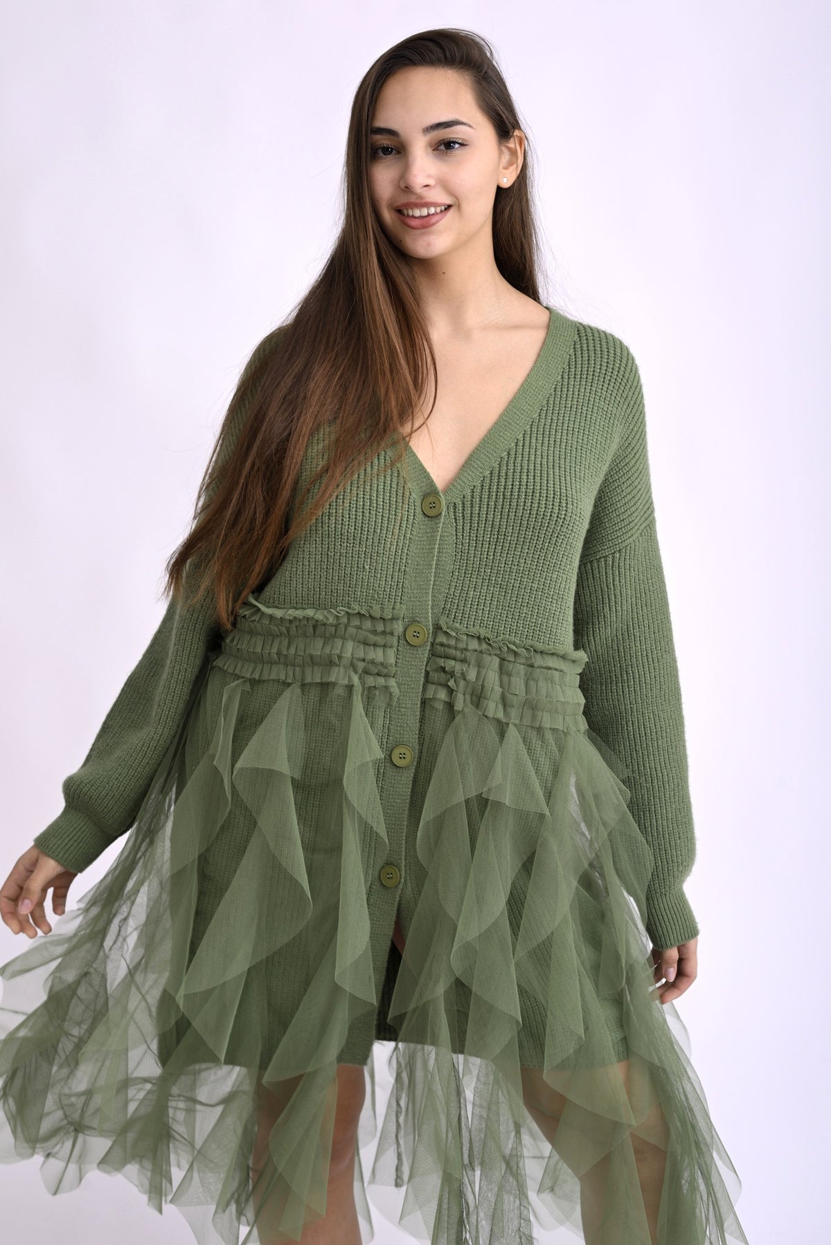 Cardigan verde cu franjuri, fotografiat din lateral, evidențiind textura și croiala lejeră.