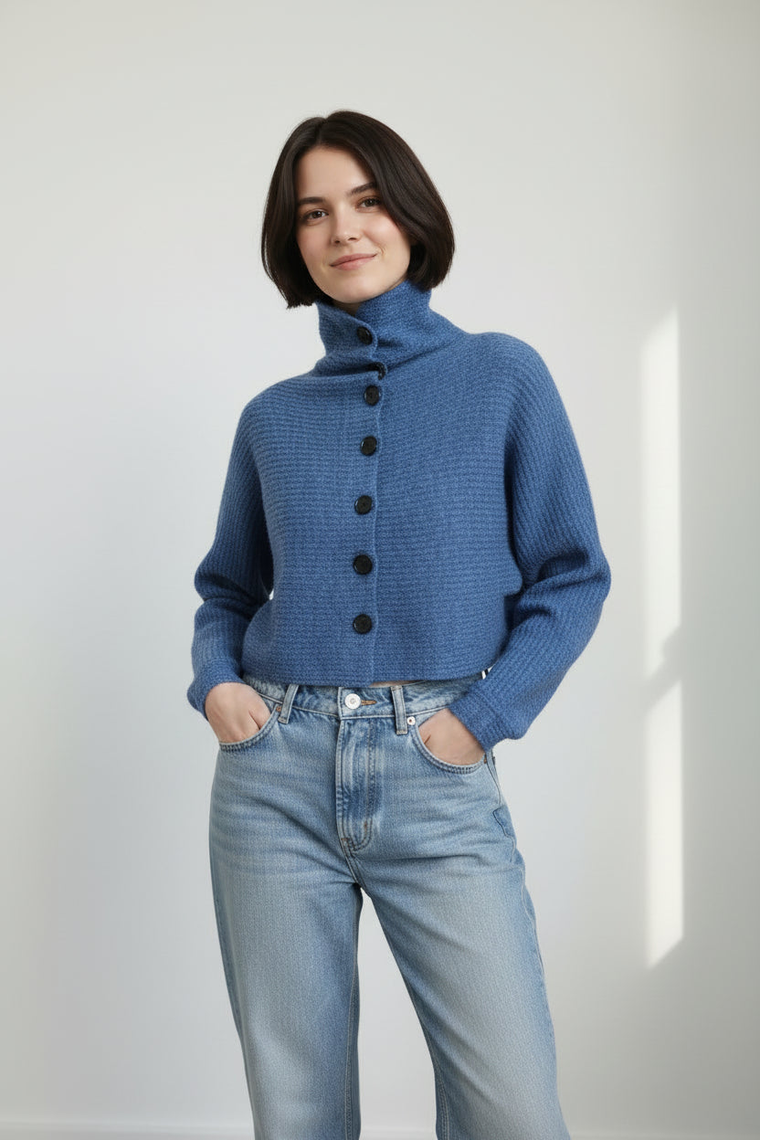 Cardigan scurt albastru, cu umeri căzuți și mâneci lungi, purtat într-o ținută de zi.