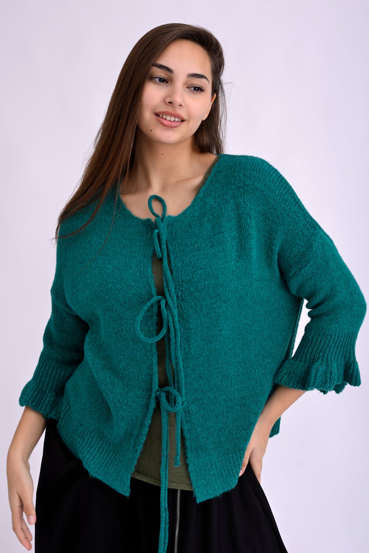 Model poartă cardigan tricotat fucsia, scurt, cu șnur frontal și umeri căzuți, prezentare din față pe fundal alb.