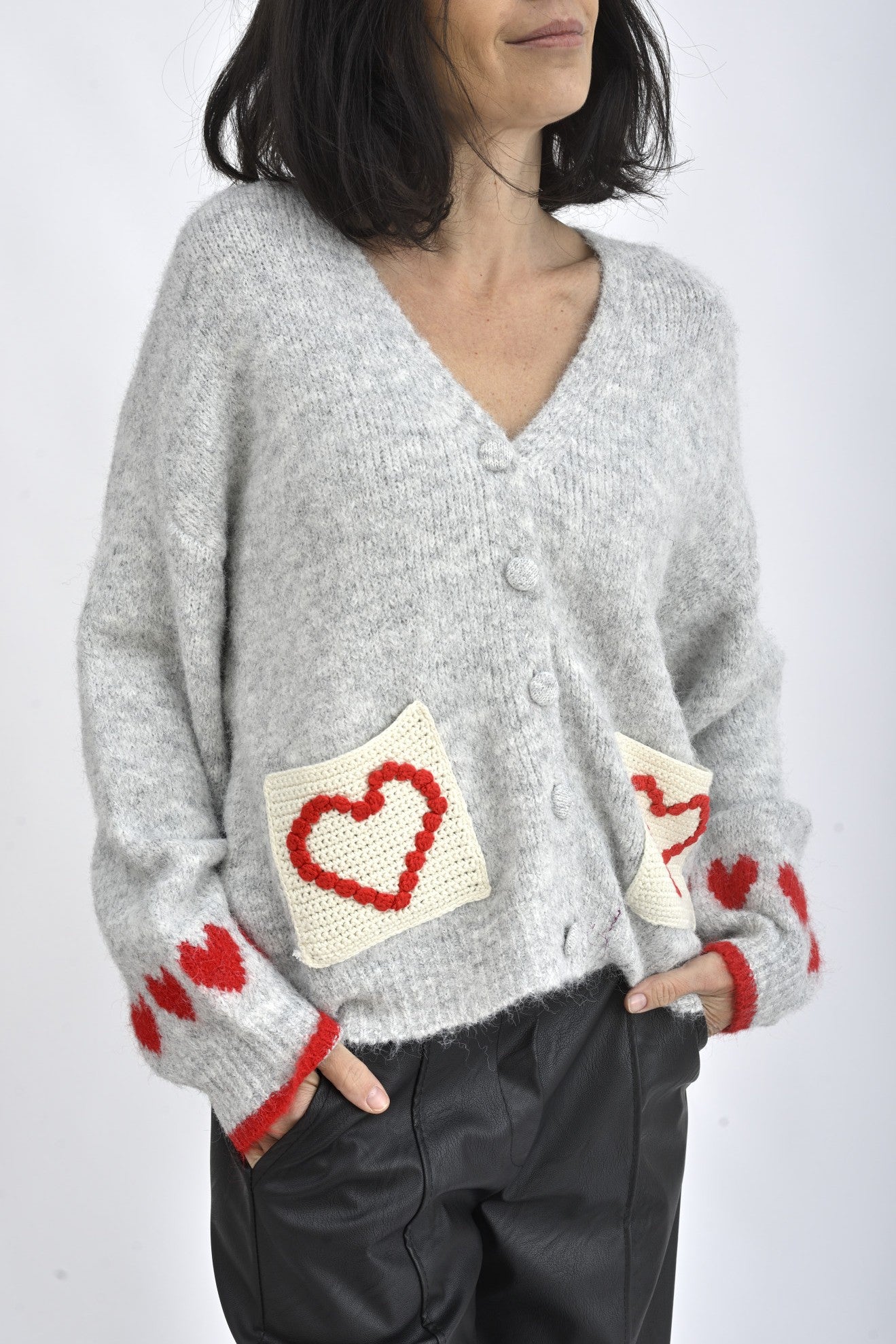 Buzunare frontale tricotate ale cardiganului gri, decorate cu aplicații în formă de inimă