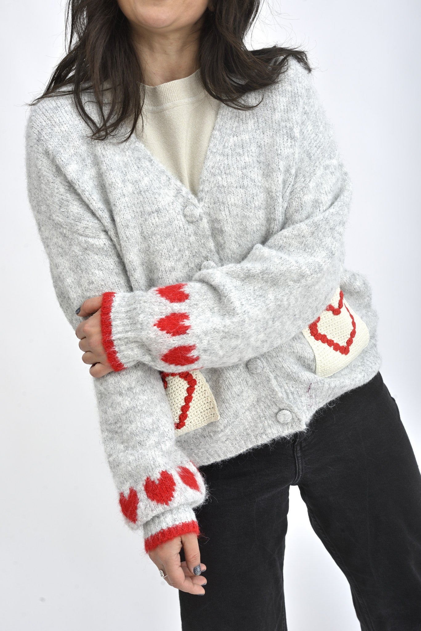 Detaliu mânecă cardigan gri cu inimioare roșii tricotate și manșetă elastică