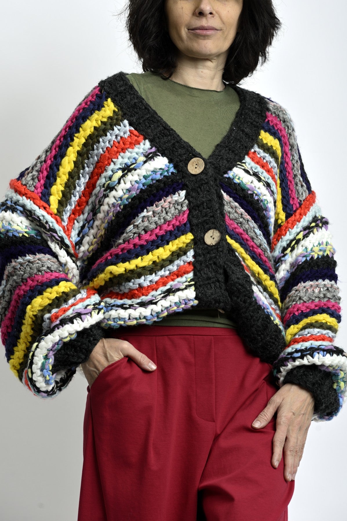 Detaliu frontal cardigan tricotat cu dungi colorate și închidere cu nasturi, textură groasă și aspect handmade.
