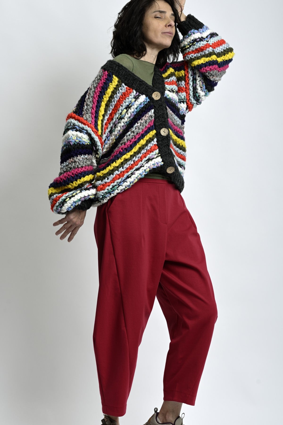 Cardigan tricotat multicolor văzut din profil, croială lejeră cu umeri căzuți și mâneci voluminoase.