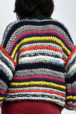 Spatele cardiganului tricotat cu dungi multicolore, fir gros și cădere relaxată pe corp.