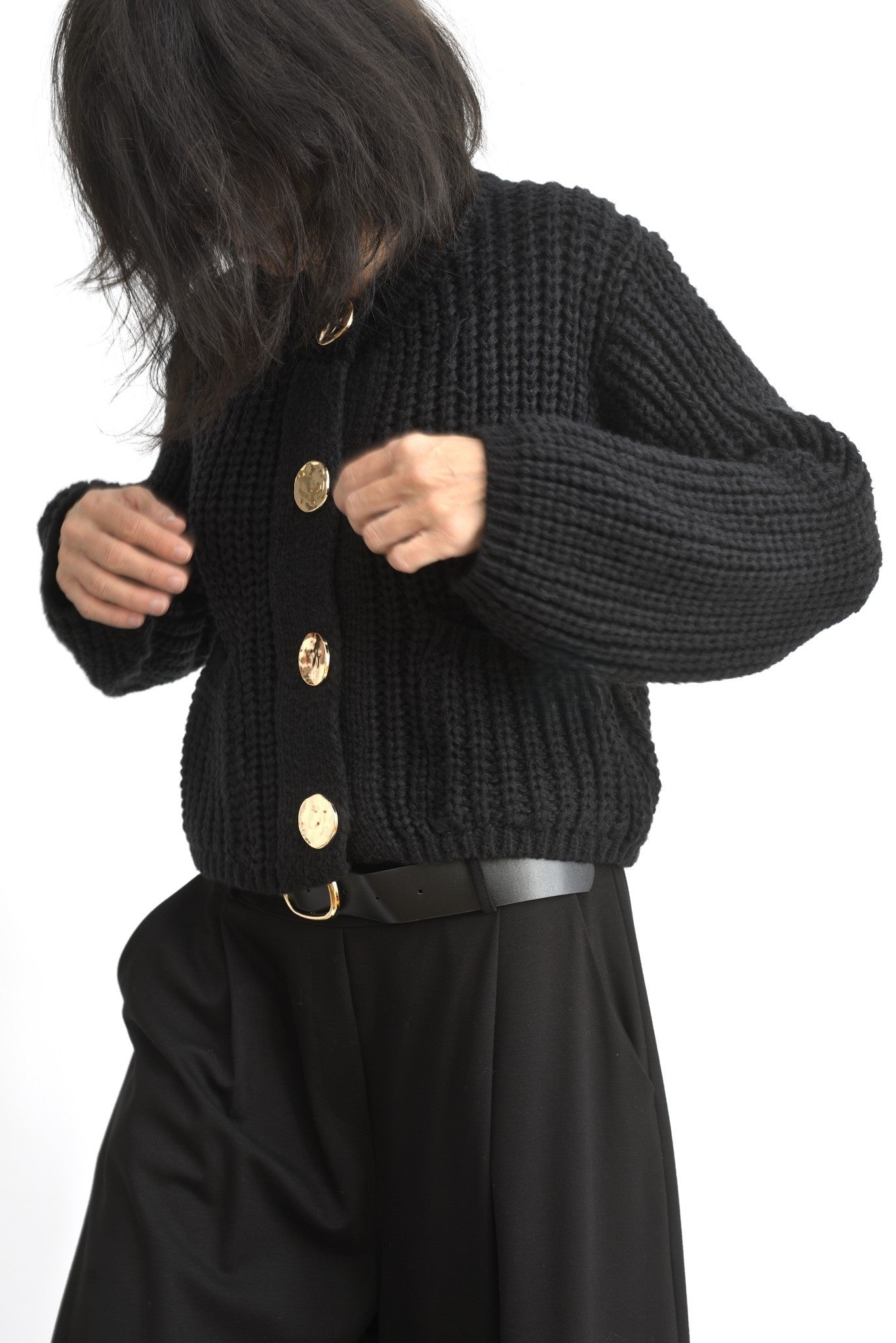 Cardigan scurt tricotat negru cu nasturi aurii, vedere laterală pe model.