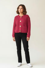 Cardigan tricotat scurt roz cu nasturi aurii, prezentat frontal pe model.