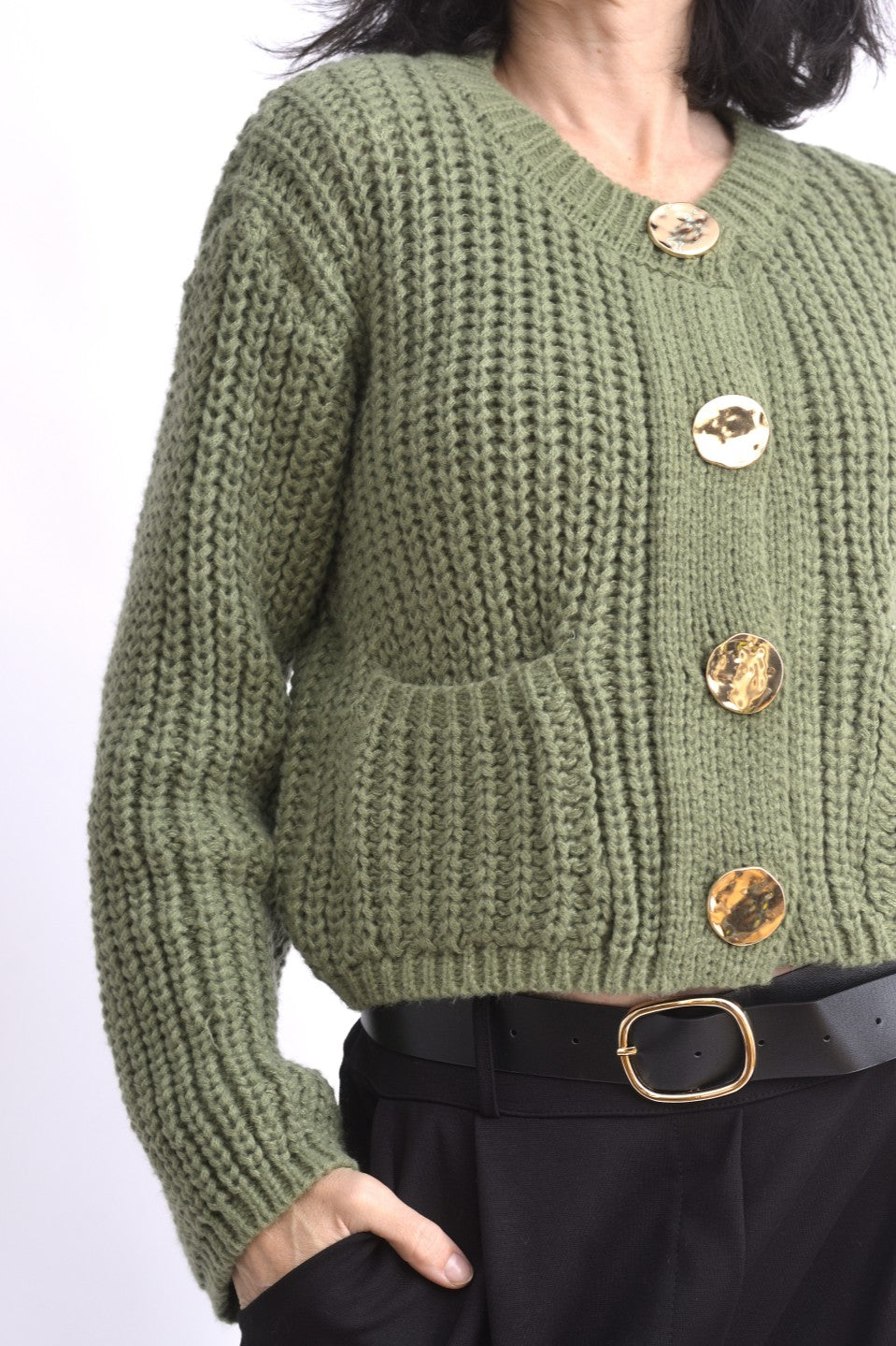 Detaliu cardigan tricotat verde cu ochiuri mari și nasturi aurii supradimensionați.