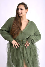 Detaliu de material al cardiganului verde cu franjuri lungi, textură moale și voluminoasă.