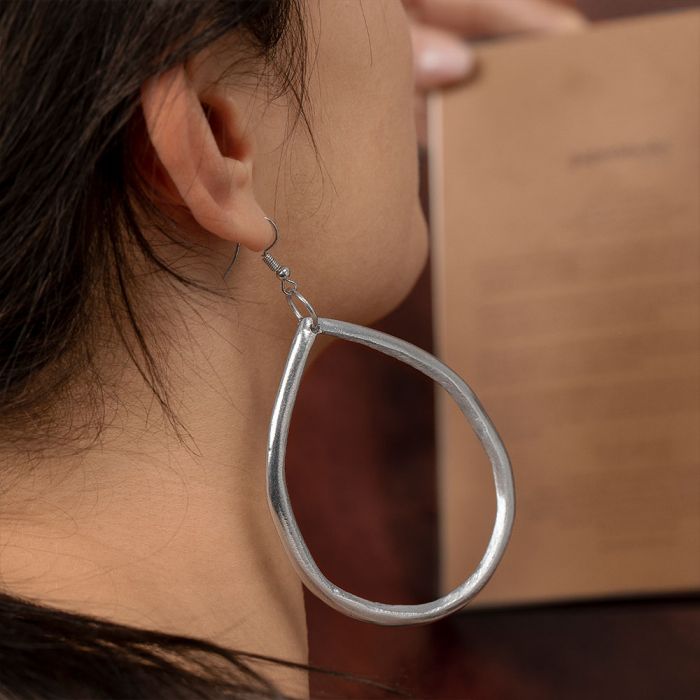 Cercei ovali neregulați din aluminiu reciclat, purtați de model; cercei ușori, cu design modern și formă organică.