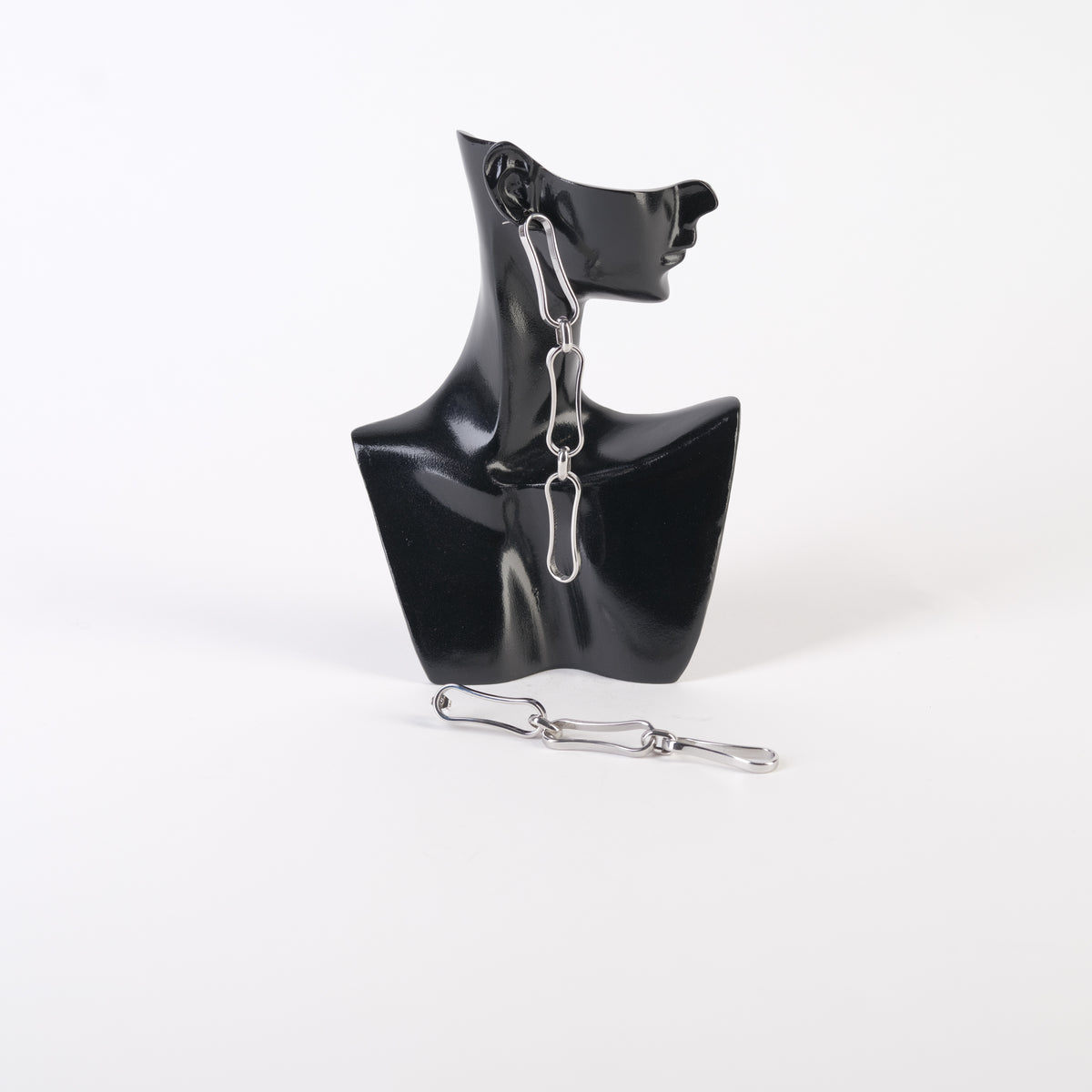 Cercei lungi din zale metalice, design statement, expuși pe un suport negru