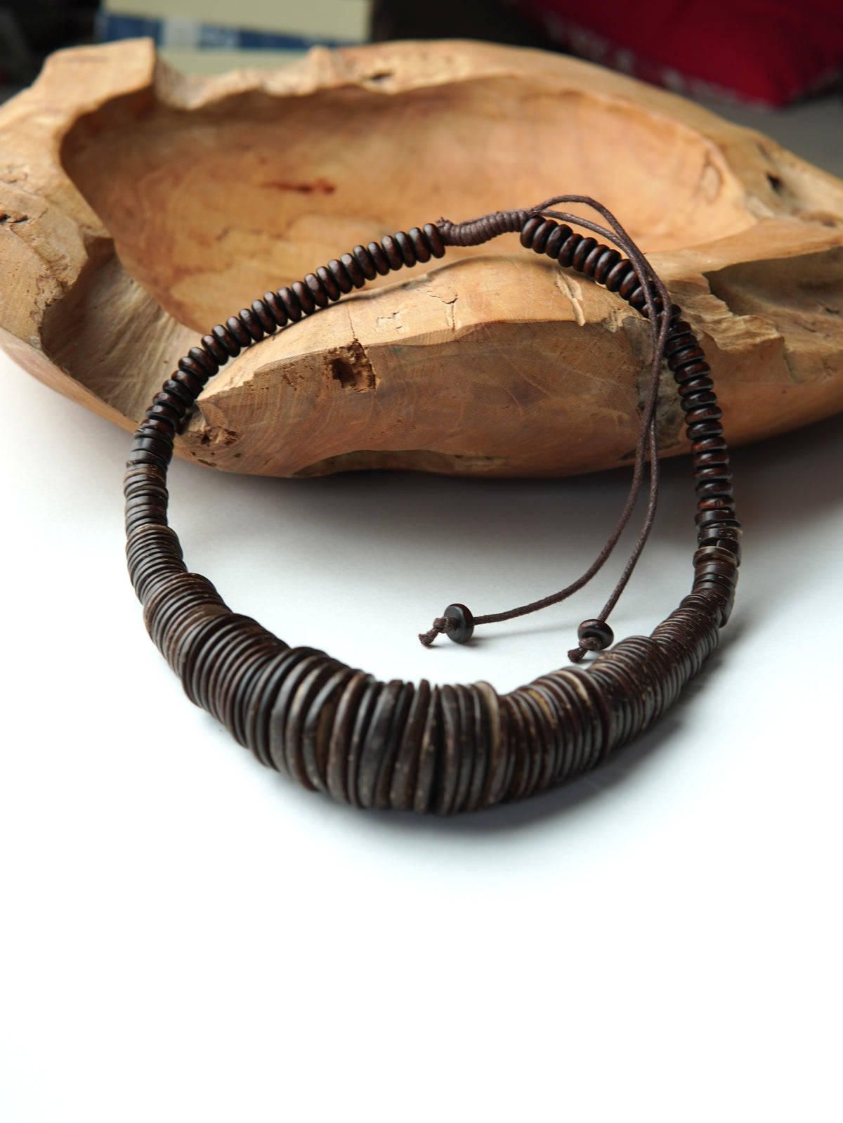 Colier cu discuri subțiri din lemn natural, așezate compact, fotografiat pe fundal cald.