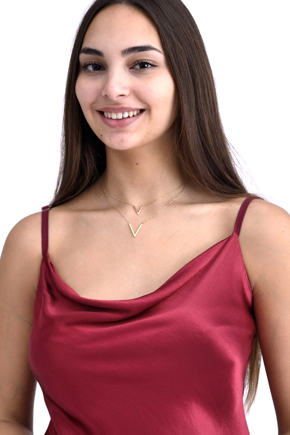 Model purtând un colier dublu auriu cu pandantive în formă de V, asortat cu un top satinat bordo, cu bretele subțiri.