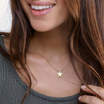 Colier delicat din alamă cu pandantiv stea, purtat la baza gâtului pentru un look minimalist și feminin.